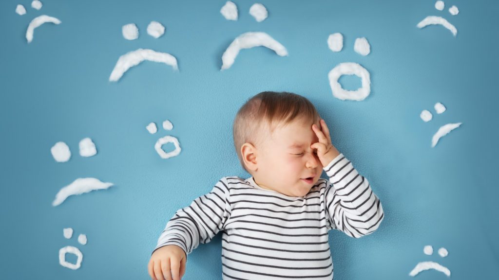 uhappy little boy on blue blanket background with sad smiley faces